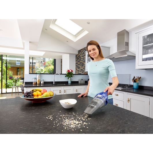 BLACKDECKER NVC115WA hand vacuum cleaning kitchen counter, fruit bowl and cereal visible.
