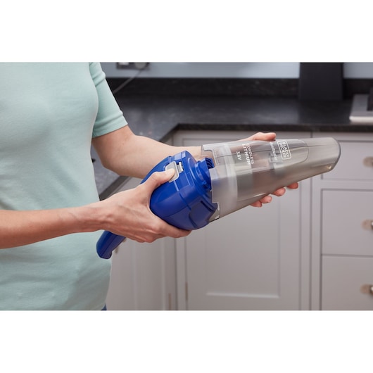 Photo of BLACKDECKER handheld vacuum NVC115WA in blue being emptied in a kitchen setting.