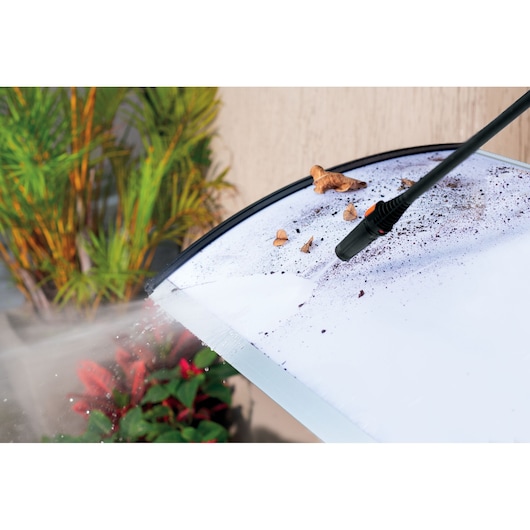 BLACKDECKER PW1450TDL pressure washer cleaning dirt and debris from outdoor glass surface, nozzle spraying water.