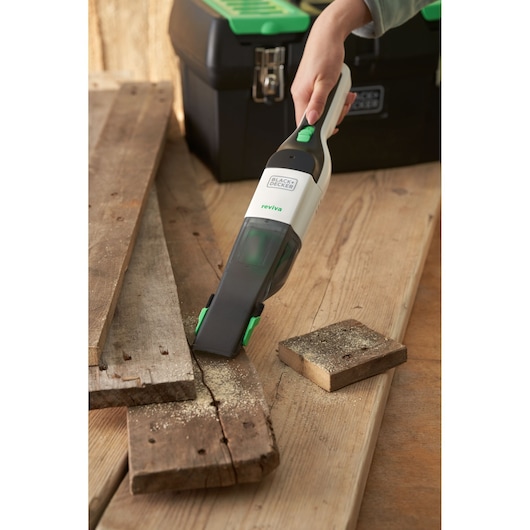 BLACKDECKER REVHV8C handheld vacuum cleaning sawdust on wood near toolbox, product in use.