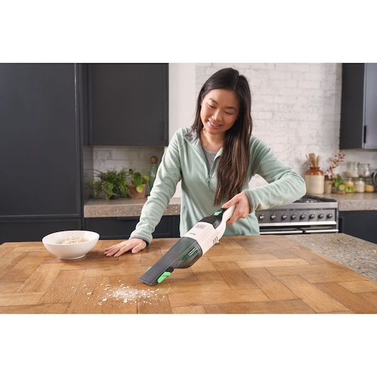 BLACKDECKER REVHV8C handheld vacuum cleaning crumbs on kitchen table, photography of product in use.