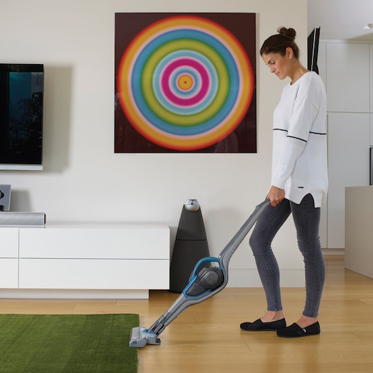 BLACKDECKER SVJ520BFS cordless stick vacuum cleaning a green rug in a modern living room.