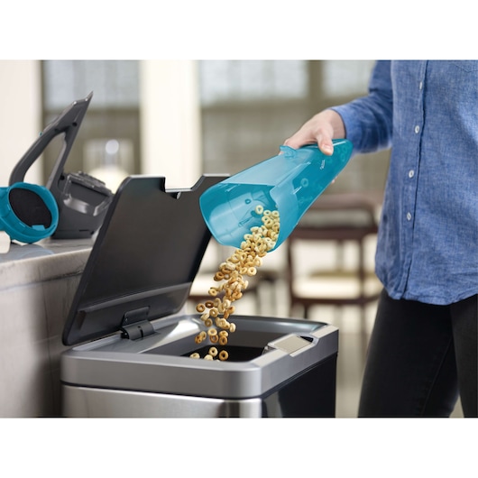 BLACKDECKER WDA320J handheld vacuum dustbin emptied into trash can, close-up indoor.