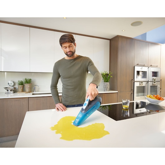 BLACKDECKER WDA320J handheld vacuum cleaning liquid spill on kitchen counter.