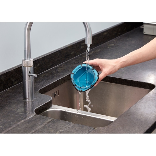 BLACKDECKER WDC115WA vacuum filter being rinsed under a kitchen faucet.