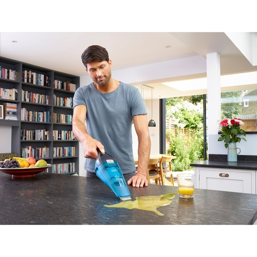 BLACKDECKER WDC215WA handheld vacuum cleaning spilled juice on kitchen counter.