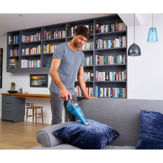 BLACKDECKER WDC215WA handheld vacuum cleaning blue cushion in modern living room.